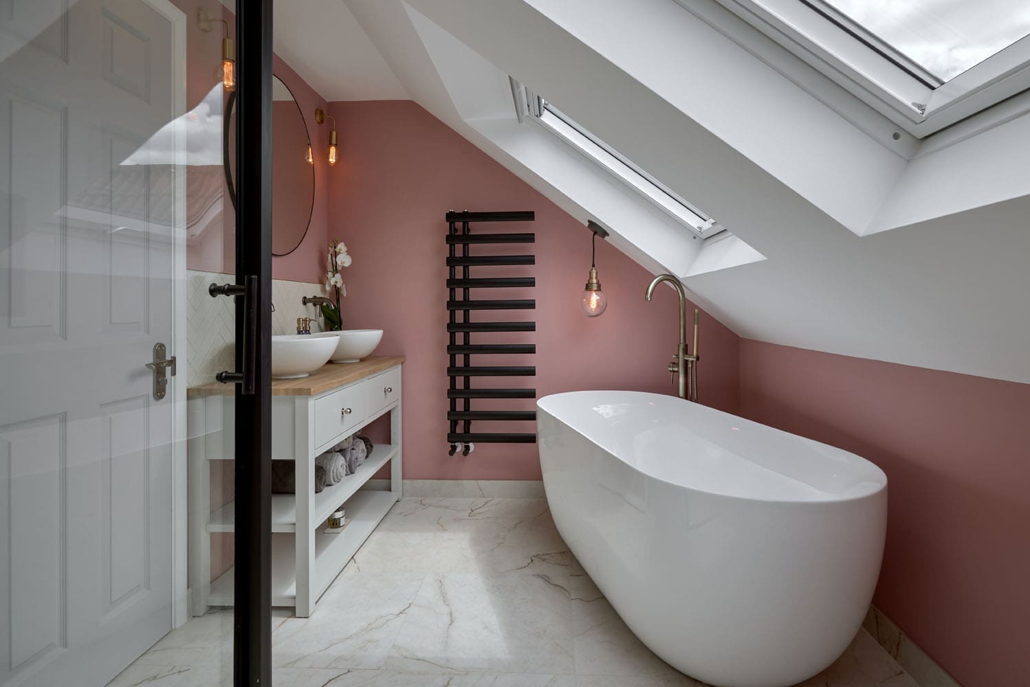 wide shot of loft bathroom with freestanding bath under sloped roof