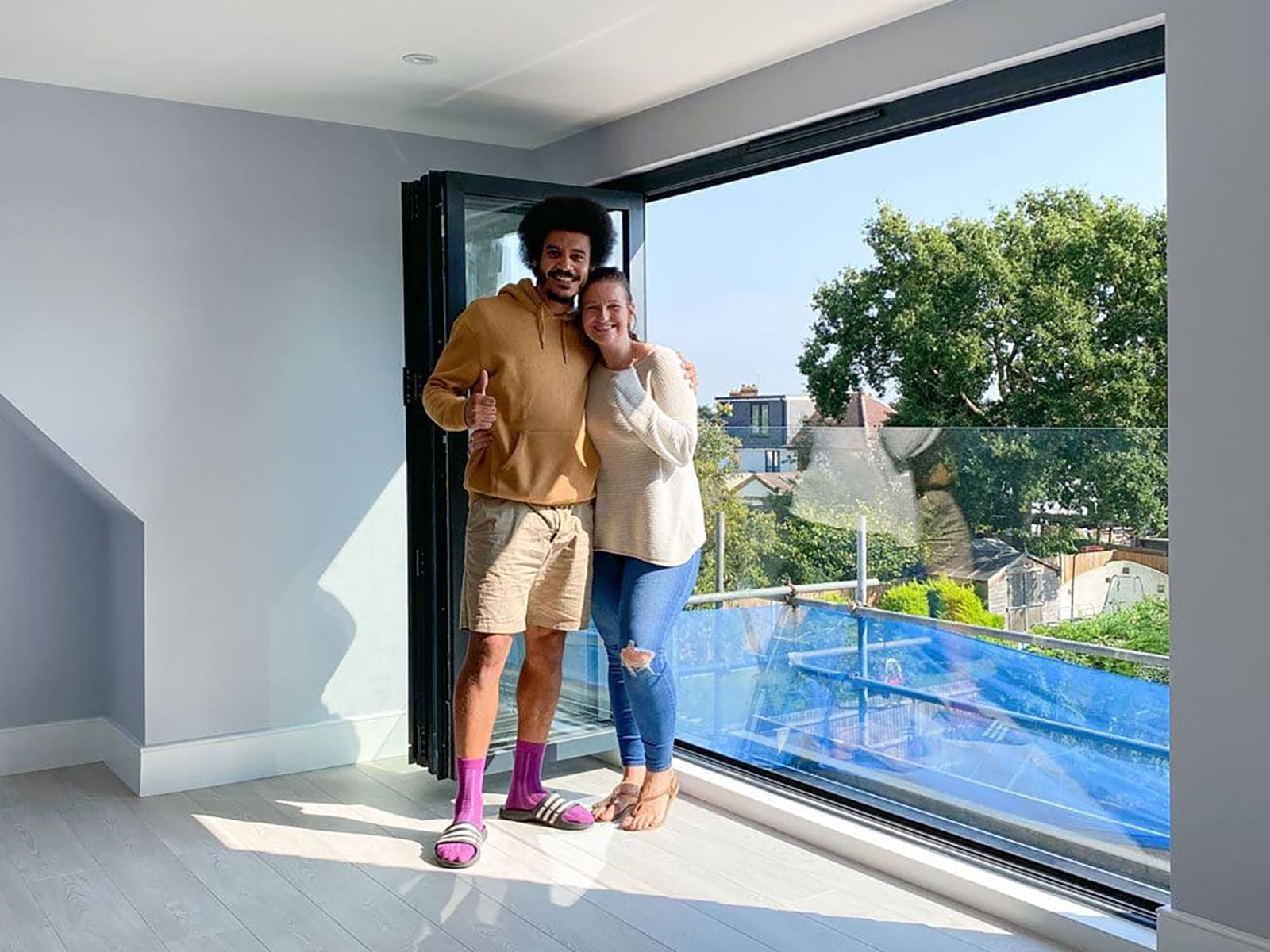 happy couple standing in loft conversion next to bifold doors