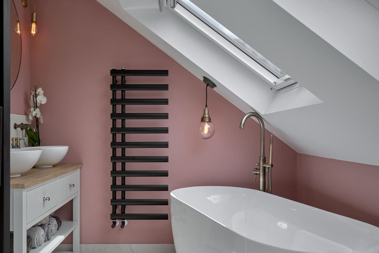 close up of rear dormer loft bathroom with dual sinks and sloped roof and freestanding bath