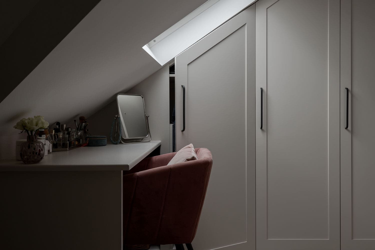 chic loft dressing room storage with makeup vanity setup under sloped ceilings of rear dormer